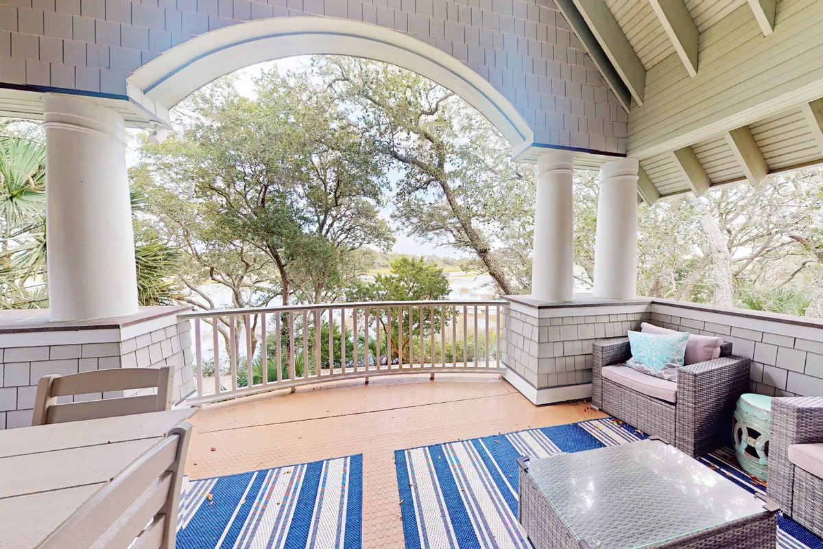 A tranquil outdoor seating area is arranged on a private deck, featuring comfortable chairs and a decorative rug. The space is surrounded by lush trees, providing both shade and privacy, and is perfect for relaxing, reading, or enjoying refreshments. The view from the deck offers a peaceful immersion in nature, ideal for sunrise coffee or entertaining guests.