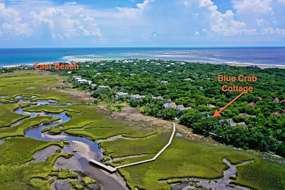 This image captures the scenic marshland with waterways stretching towards East Beach, with Blue Crab Cottage nestled at the edge. The tranquil setting is perfect for family nature exploration, birdwatching, and photography—key activities described in the section.